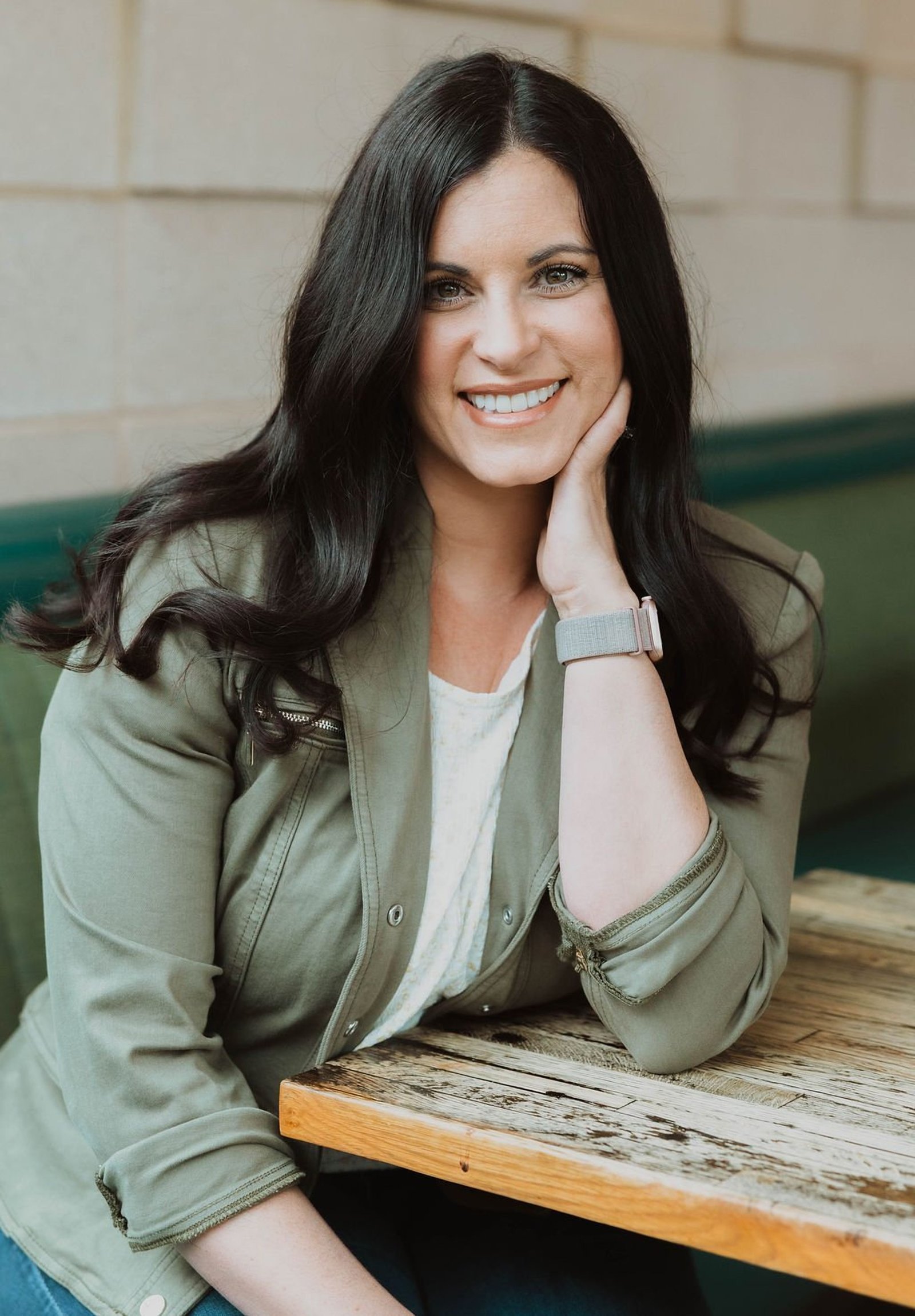 Keri Hinterreiter, co-founder of The Collective for Designers, smiling with her chin resting on her hand at a restaurant table